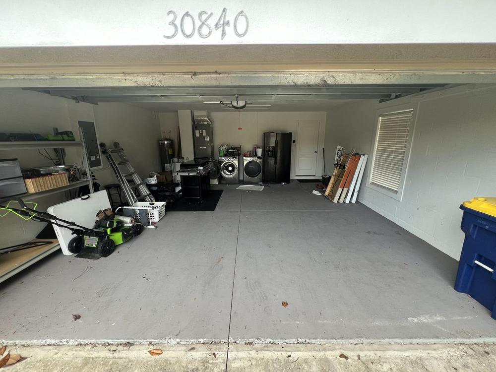 The same garage under the same 30840 header beam, floor swept end to end, with only the washer, dryer and a bin left standing against the right wall.