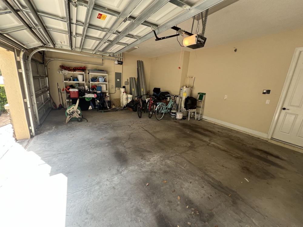 The same beige garage seen from the driveway, floor clear across its full width, with a bicycle and the shelving that was always meant to be there left along the side wall.