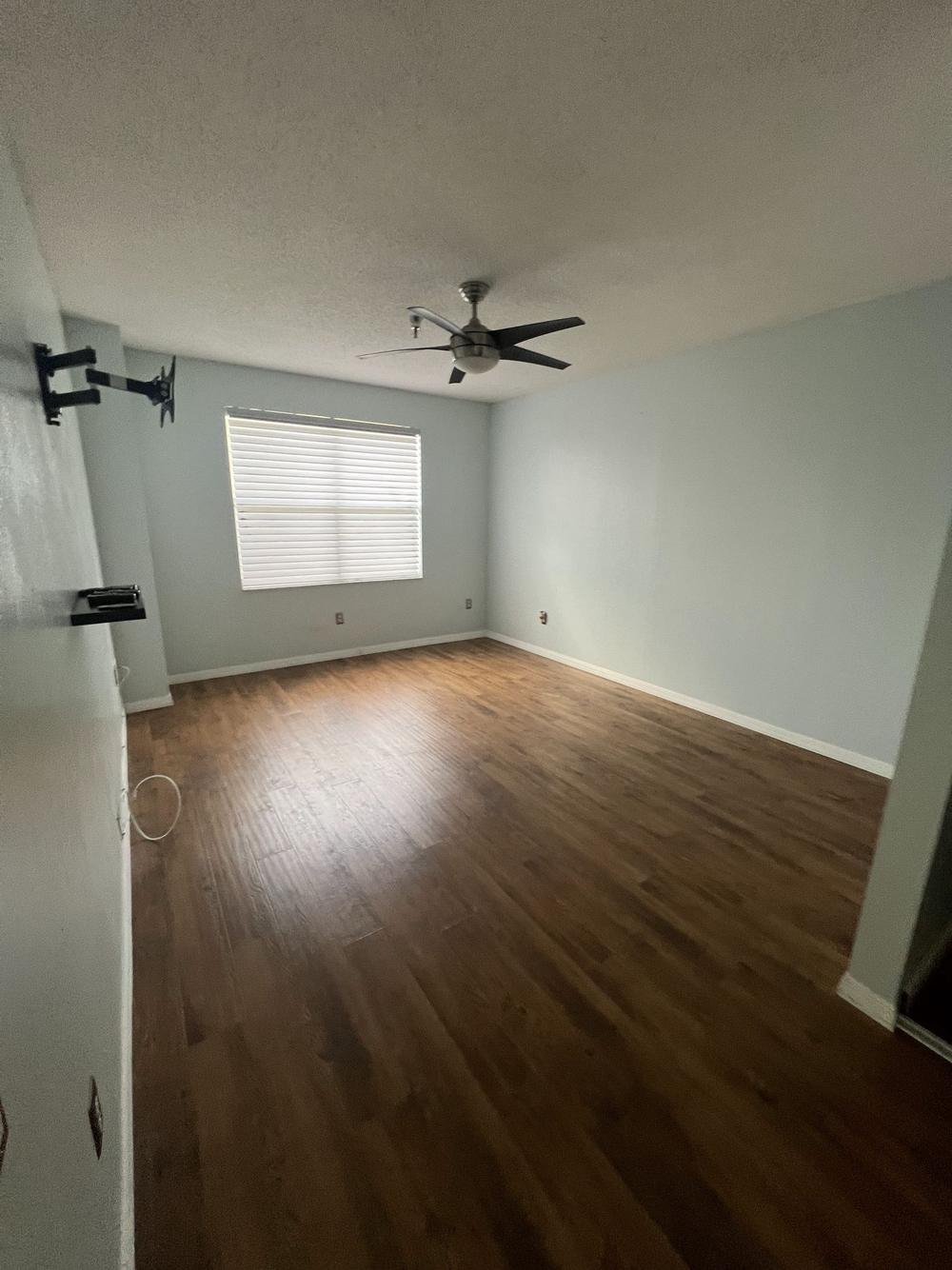 An emptied rental unit with a bare wood floor and clean walls, ready to be photographed and re-listed.